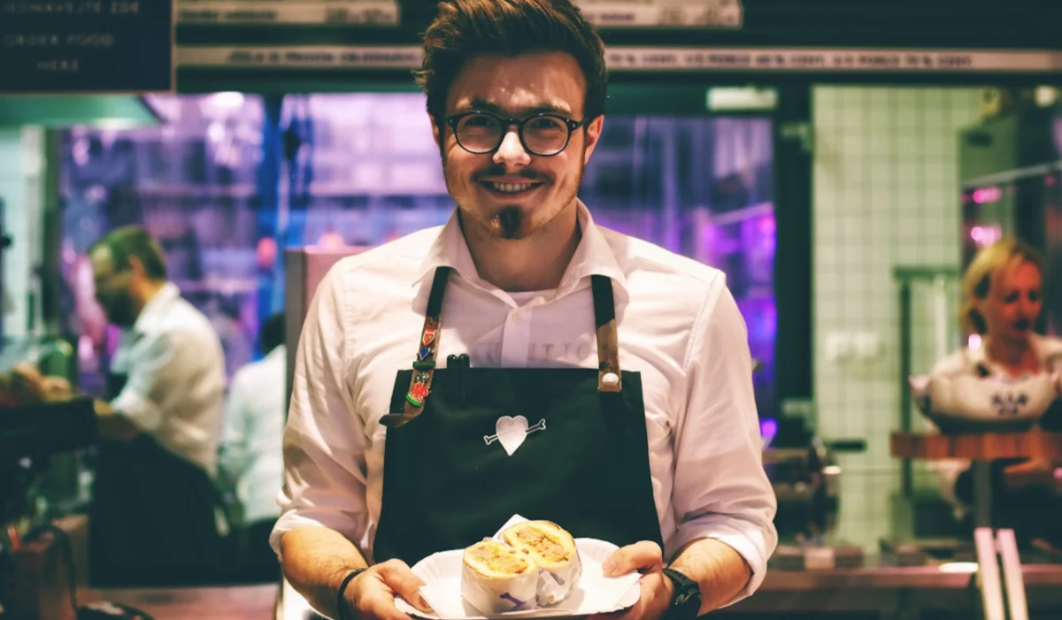 Serveur souriant apportant un plat en salle